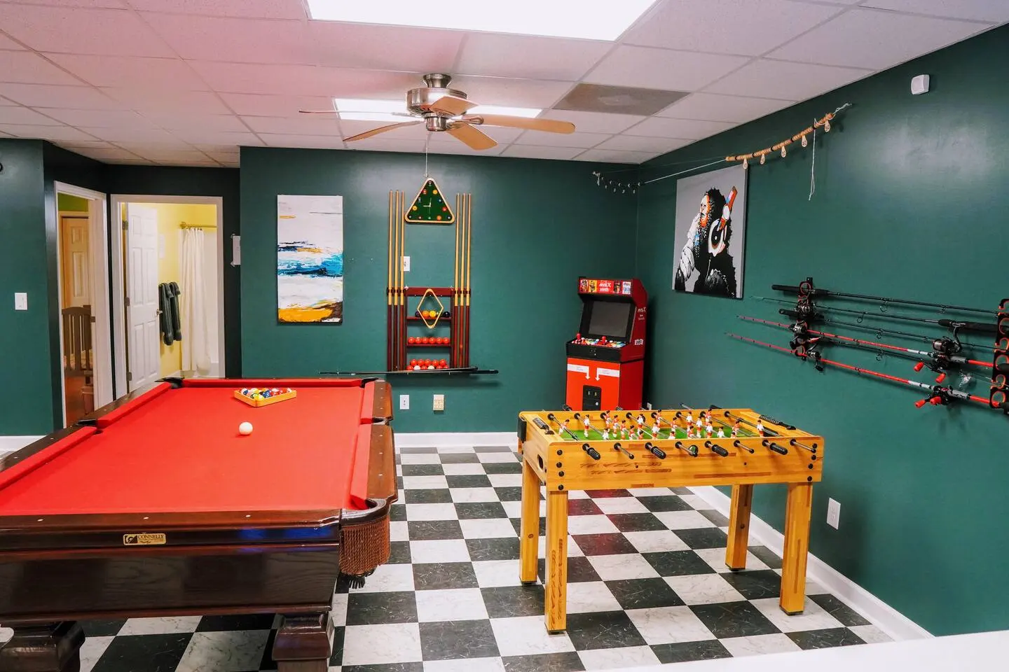 Game room with a red pool table, foosball, an arcade cabinet, and a checkered floor