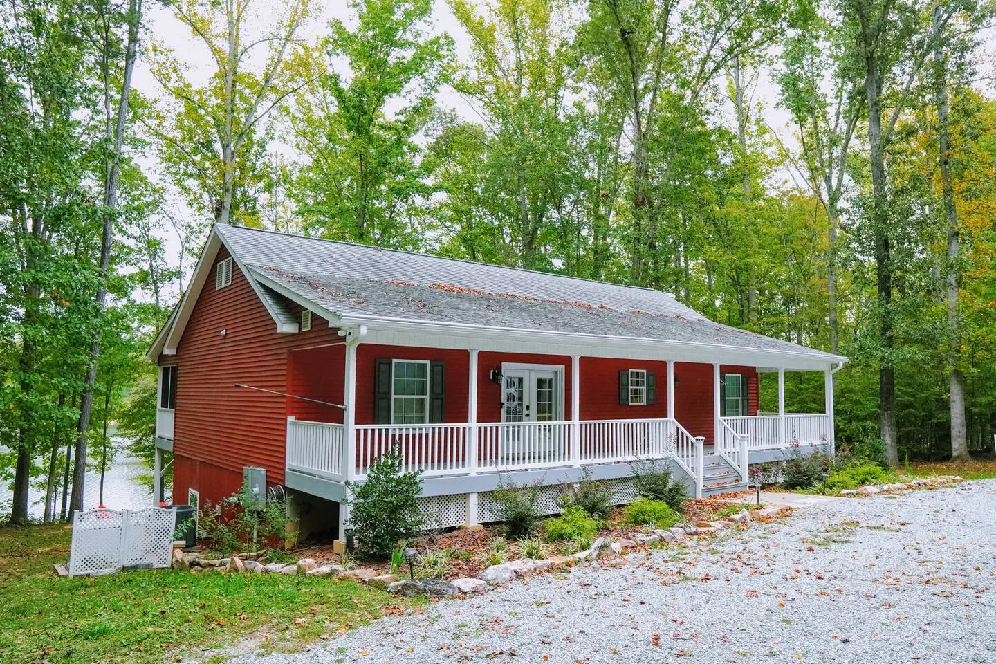 The red lake house and its 1.5 wooded acres seen from the gravel drive