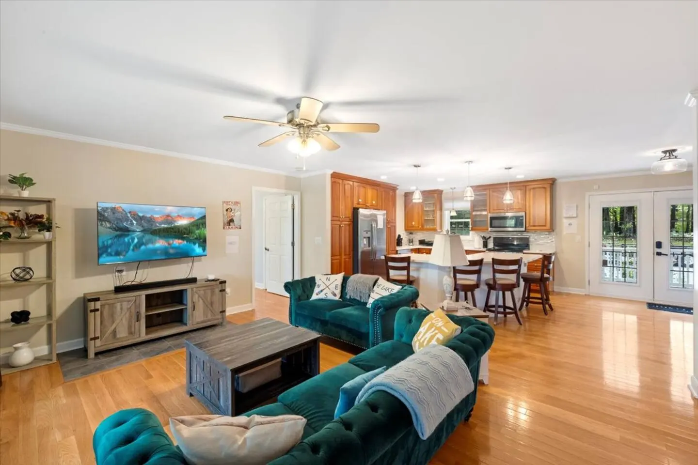 Living room seating area with teal sofas, a ceiling fan, and lake views