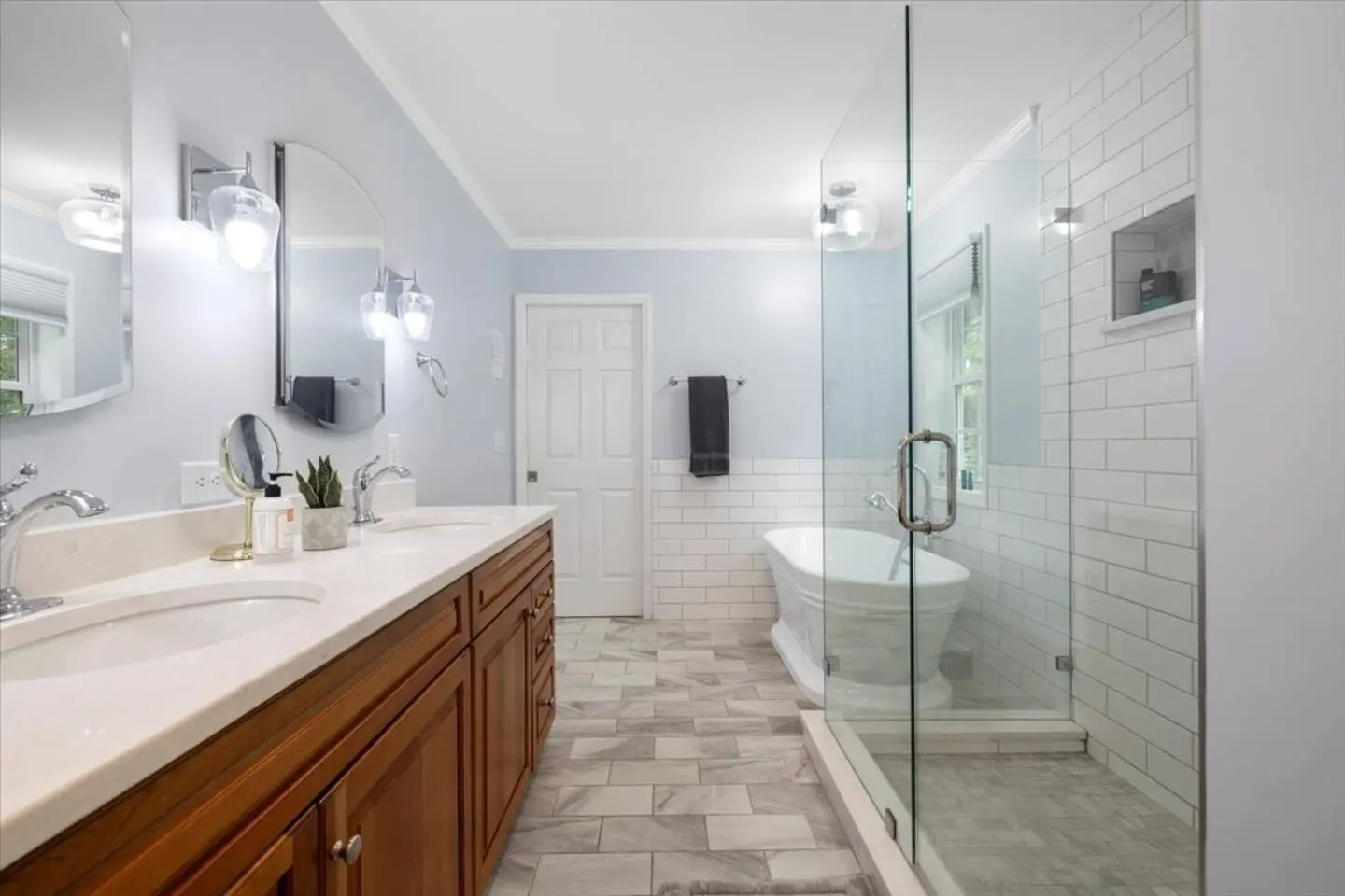 Primary bathroom with a double vanity, glass walk-in shower, and soaking tub