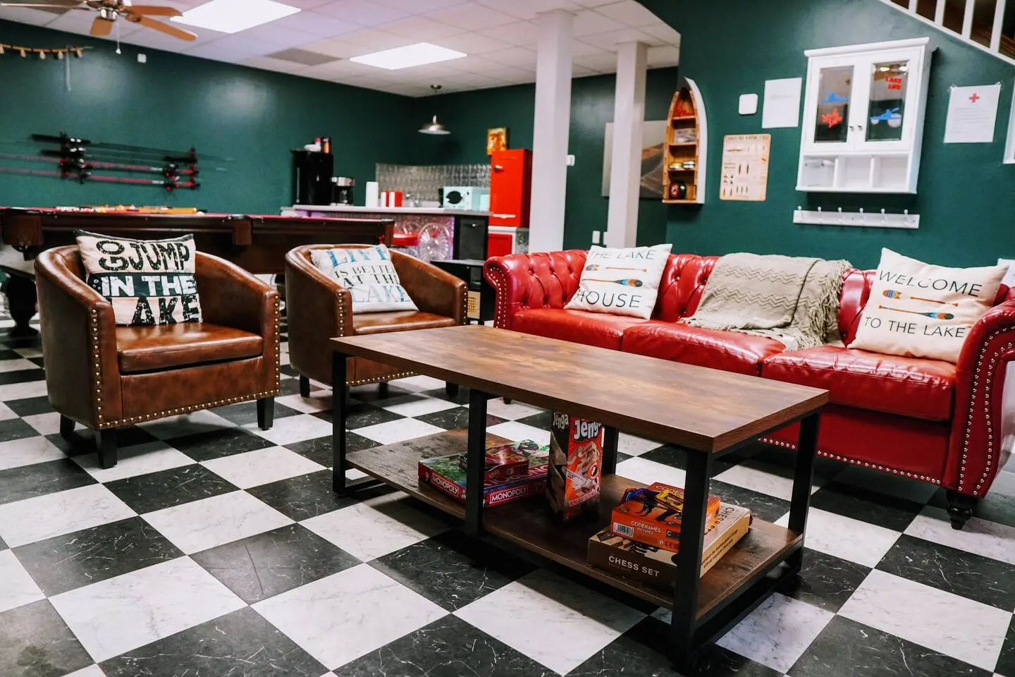 Game-room lounge with red leather sofas, board games, and a bar area