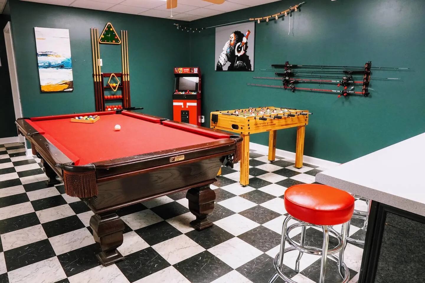 Wide view of the game room with pool table, foosball, and arcade