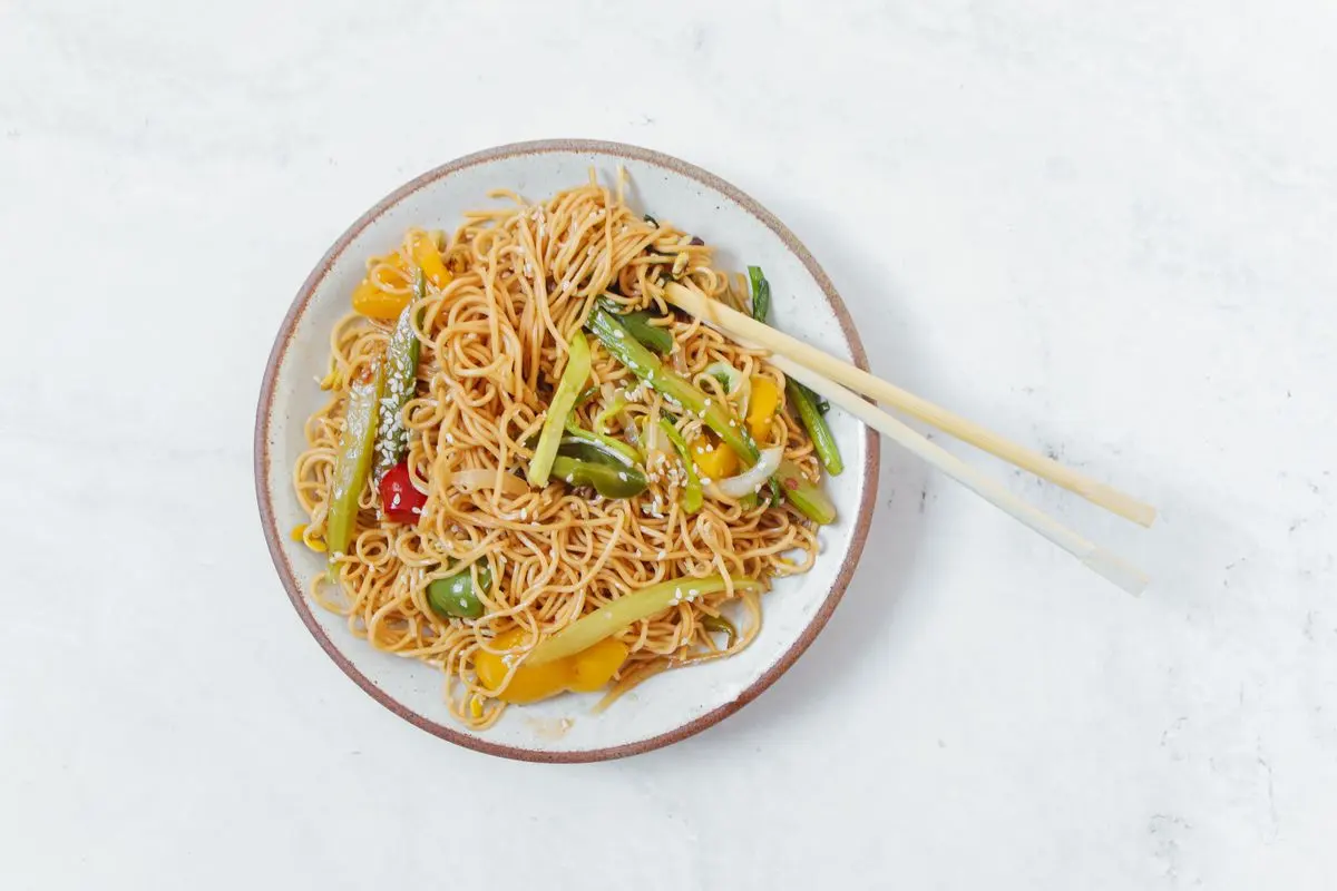 Stir-fried noodles with vegetables and chopsticks on a plate